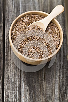 Flax seeds in bowl and spoon on dark wooden background