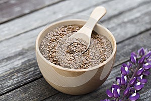 Flax seeds in bowl and spoon on dark wooden background