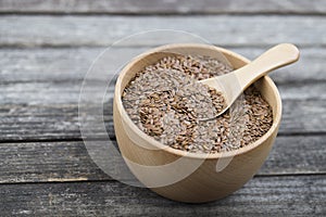 Flax seeds in bowl and spoon on dark wooden background