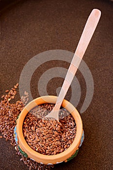 Flax seeds in a bowl with wooden spoon, selective focus