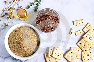 Flax seeds, flax flour, butter and crackers with sprouts and flax bolls on a light background