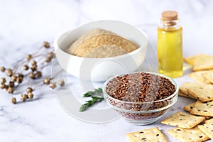 Flax seeds, flax flour, butter and crackers with sprouts and flax bolls on a light background