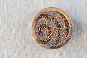 Flax seeds Linum usitatissimum are useful in a bowl of olive wood on flax. Product for beauty and health. Proper nutrition