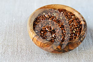 Flax seeds Linum usitatissimum are useful in a bowl of olive wood on flax. Product for beauty and health. Proper nutrition