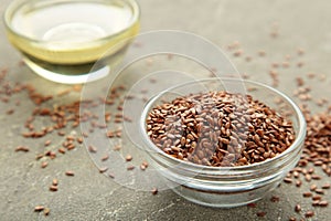 Flax seeds and oil in bottle on grey background