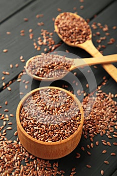 Flax seeds on wooden bowl and spoon on black background