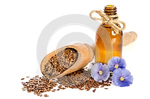 Flax seeds in wooden scoop, bottle with oil and beauty flowers