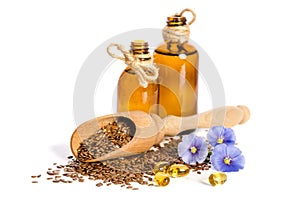 Flax seeds in the wooden scoop, bottle with oil and beauty flowers