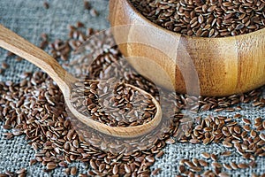flax seeds in a wooden spoon on a background of burlap in a rustic style