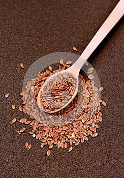 Flax seeds in a wooden spoon on a metal background, selective fo