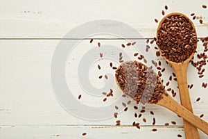 Flax seeds on wooden spoon on white background