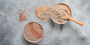 Flaxseed flour in a bowl in a bowl. Gray concrete grunge background. Top view, banner.