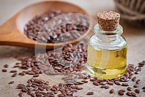 Flaxseed oil in bottle and brown flax seeds on wooden spoon