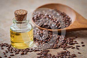 Flaxseed oil in bottle and brown flax seeds on wooden spoon