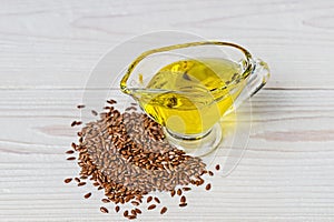 Flaxseed oil in a glass gravy boat. Flax seeds on a white background