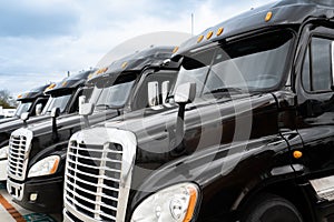 Fleet of black 18 wheeler semi trucks