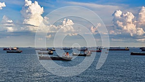 Fleet of cargo vessels navigating the open waters of Singapore, their hulls gleaming in the sunlight