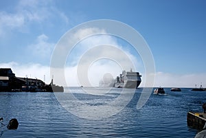 Fleet of cruise ships sailing through a dense fog in the harbor of Qaqortoq, Greenland