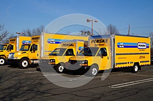 A fleet of yellow Penske rental trucks