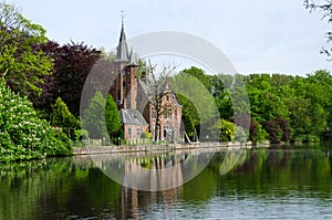 Flemish style castle reflecting in Minnewater lake in Bruges