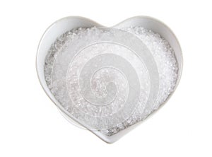 Fleur de sel in a heart-shaped bowl on white