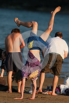 Adolescente sulla spiaggia, facendo una verticale con i suoi amici accanto a lui.