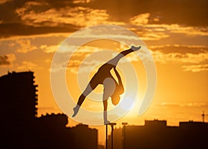 Flexible acrobat doing handstand on the cityscape background during dramatic sunset. Concept of willpower, control and