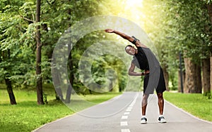 Flexible african sportsman stretching in public park