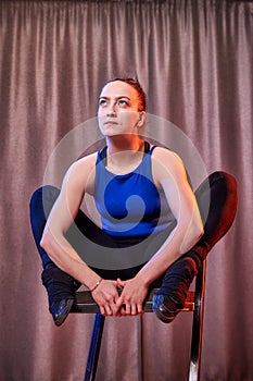 Flexible beautiful gymnast girl doing gymnastic exercises with chair in the hall or on the stage. Young woman jumping in sport