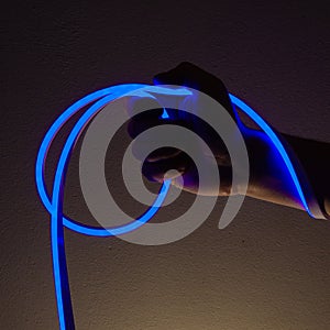 Flexible blue led tape neon in hand on black background