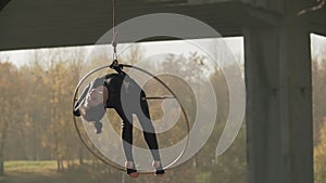 Flexible brunette with bare feet hanging in ring for aerial acrobatics in slo-mo