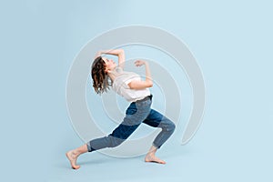 Flexible contemporary dancer in a lunge, arching herself back. In a studio.