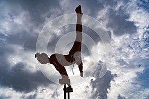 Flexible female circus Artist doing handstand against amazing cloudscape. Motivation, passion and achievement concept