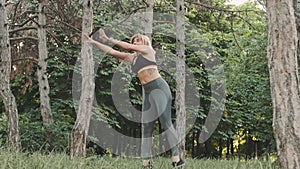 Flexible female gymnast doing acrobatic tricks in the park, slow motion