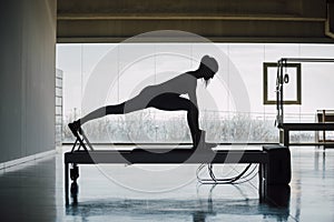 Flexible Female Using Pilates Reformer Machine In Gym