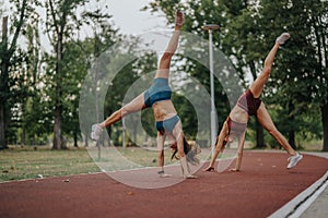 Flexible females perform impressive flips and cartwheels outdoors. Inspiring evening training in nature showcases their