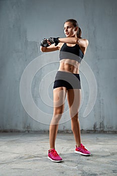 Flexible fitnesswoman stretching arms before training.