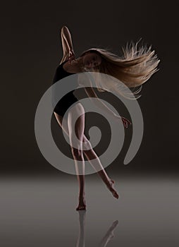 Flexible girl with long blonde hair dancing. Flying hair.