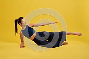 Flexible girl lying on side, raising arm and leg.