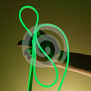 Flexible green led tape neon in hand on black background