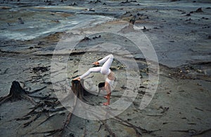 Flexible gymnast girl in a beautiful pose on a background of apocalyptic landscape in the desert