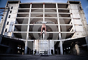 Flexible male circus Artist keep balance by hands in the concrete structure. symmetry and uniformity concept.