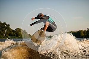 flexible man jumping on a wakesurf board over river waves photo