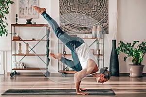 Flexible man performing Flying Crow asana at home