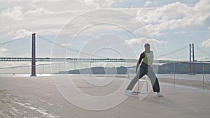 Flexible man training embankment alone. Man showing contemporary dance sea beach