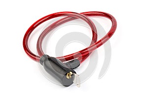 Flexible red bicycle cable with key on white background.  Security and safety concept
