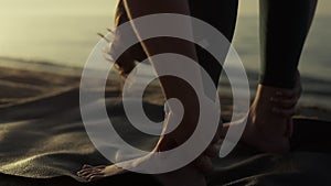 Flexible sportswoman bending body to feet on beach closeup. Yoga woman training