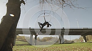 Flexible woman hanging in ring for aerial acrobatics