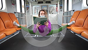 Flexible woman wearing mask sitting on the split in the subway and reading book. Concept of possibility, creativity and