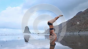 Flexible yoga woman stretching forward bend touching forehead to knees outdoors sunset sea beach close up. Professional